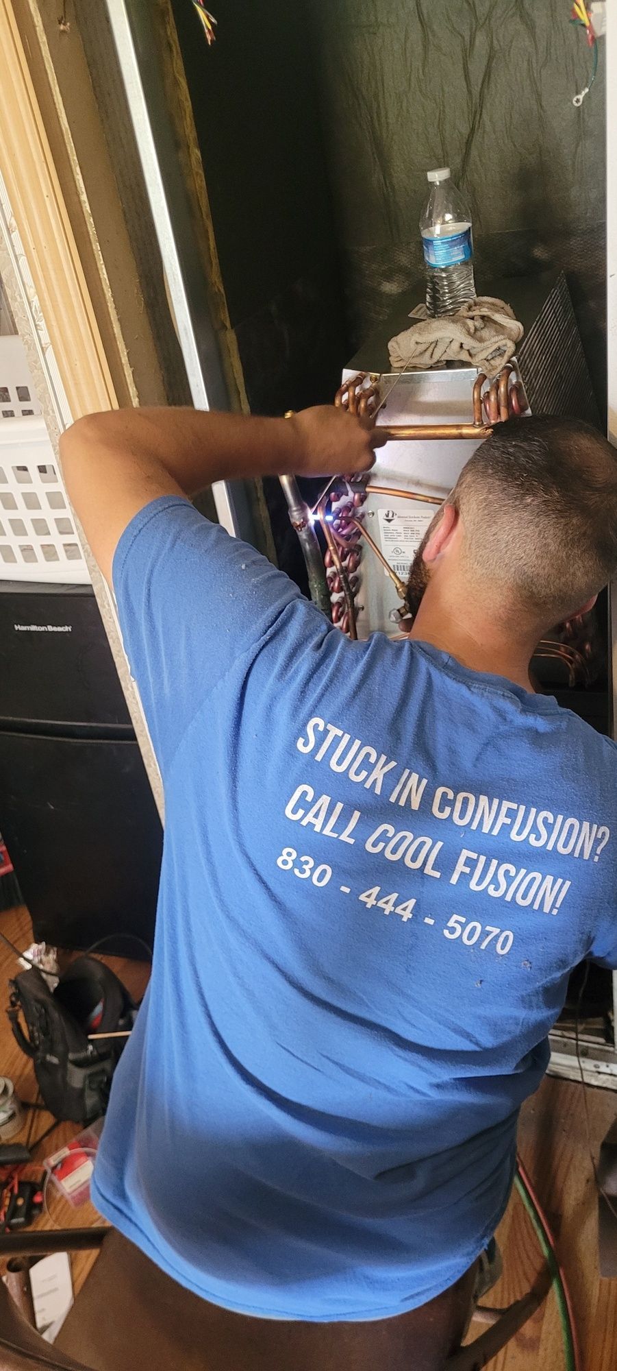 A man in a blue shirt is working on a refrigerator.