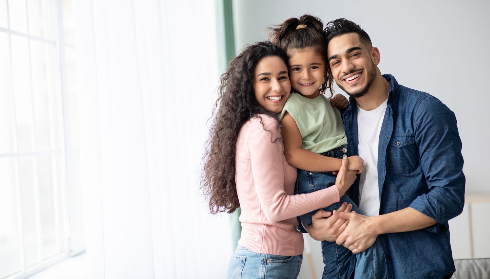 A family is posing for a picture together in front of a window.