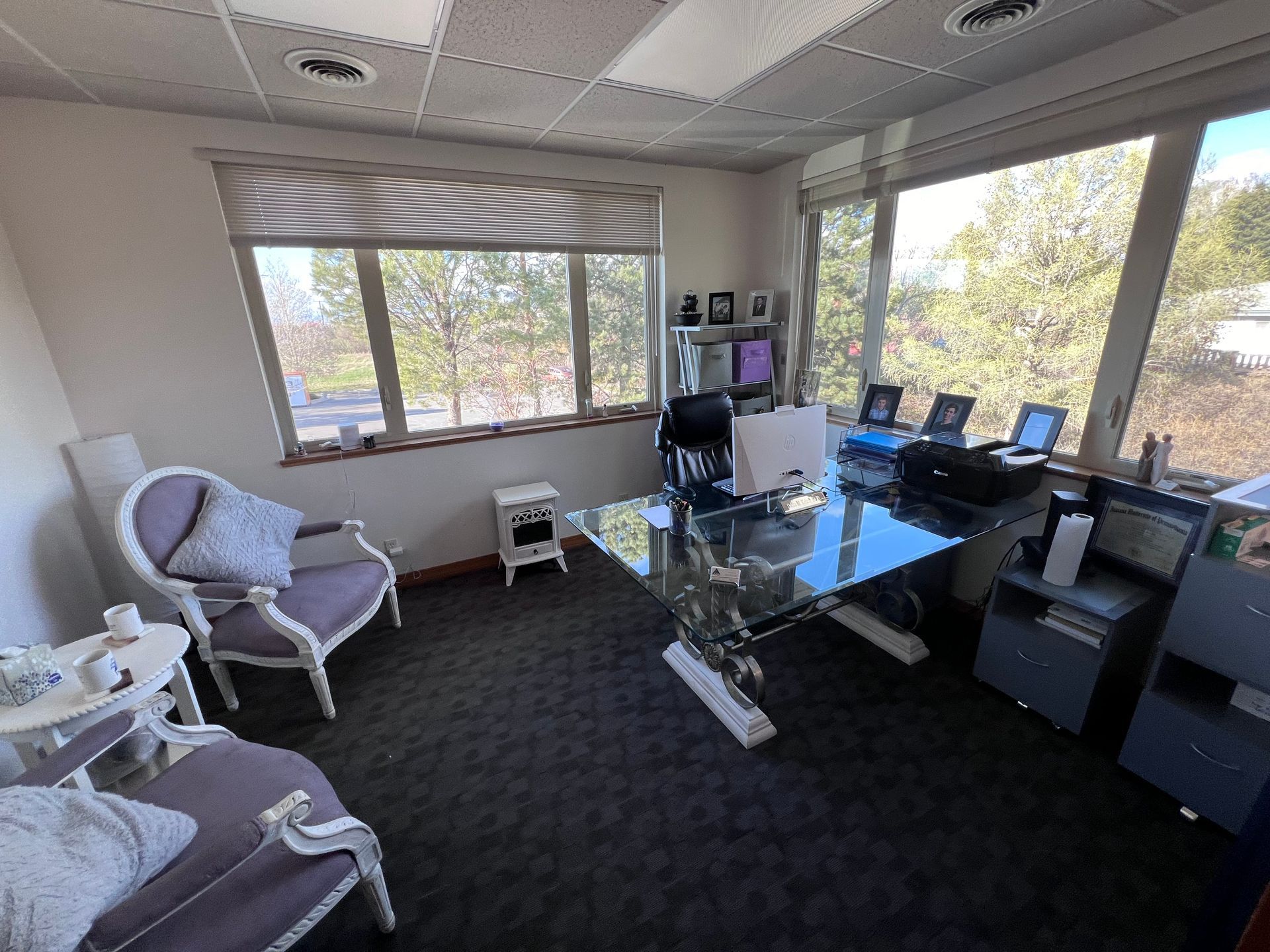 A room with a desk , chairs , and windows.