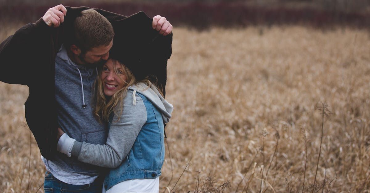 A man and a woman are hugging in a field.