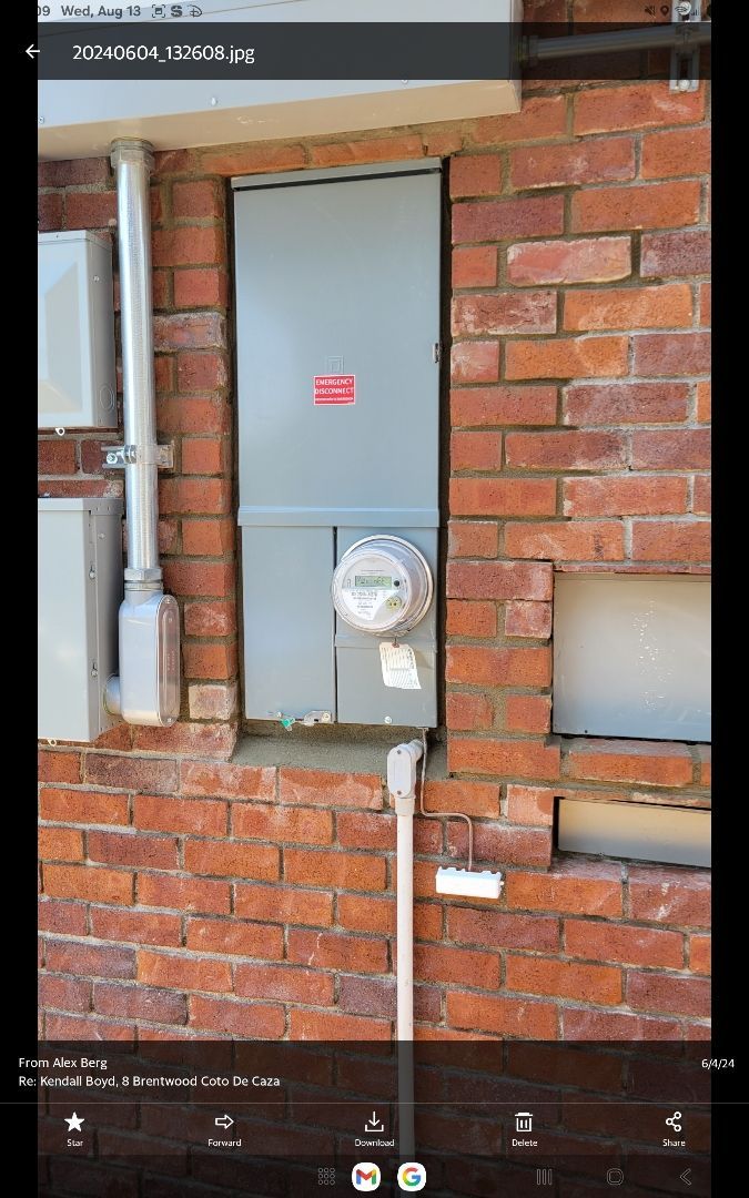 Electrical panel and meter on brick wall. Gray metal cabinet with meter and conduits.