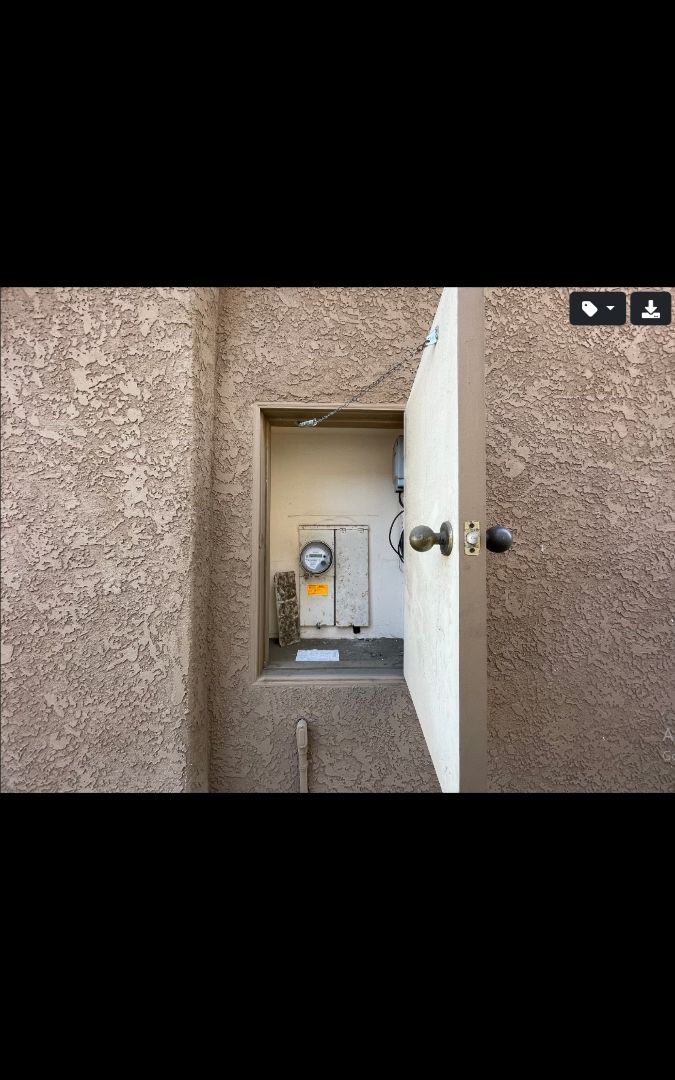 Ajar door reveals utility box recessed in a textured, brown wall.