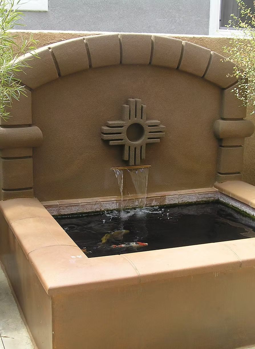 Southwestern-style outdoor water fountain with a Zuni sun symbol, flowing into a dark-bottomed basin.