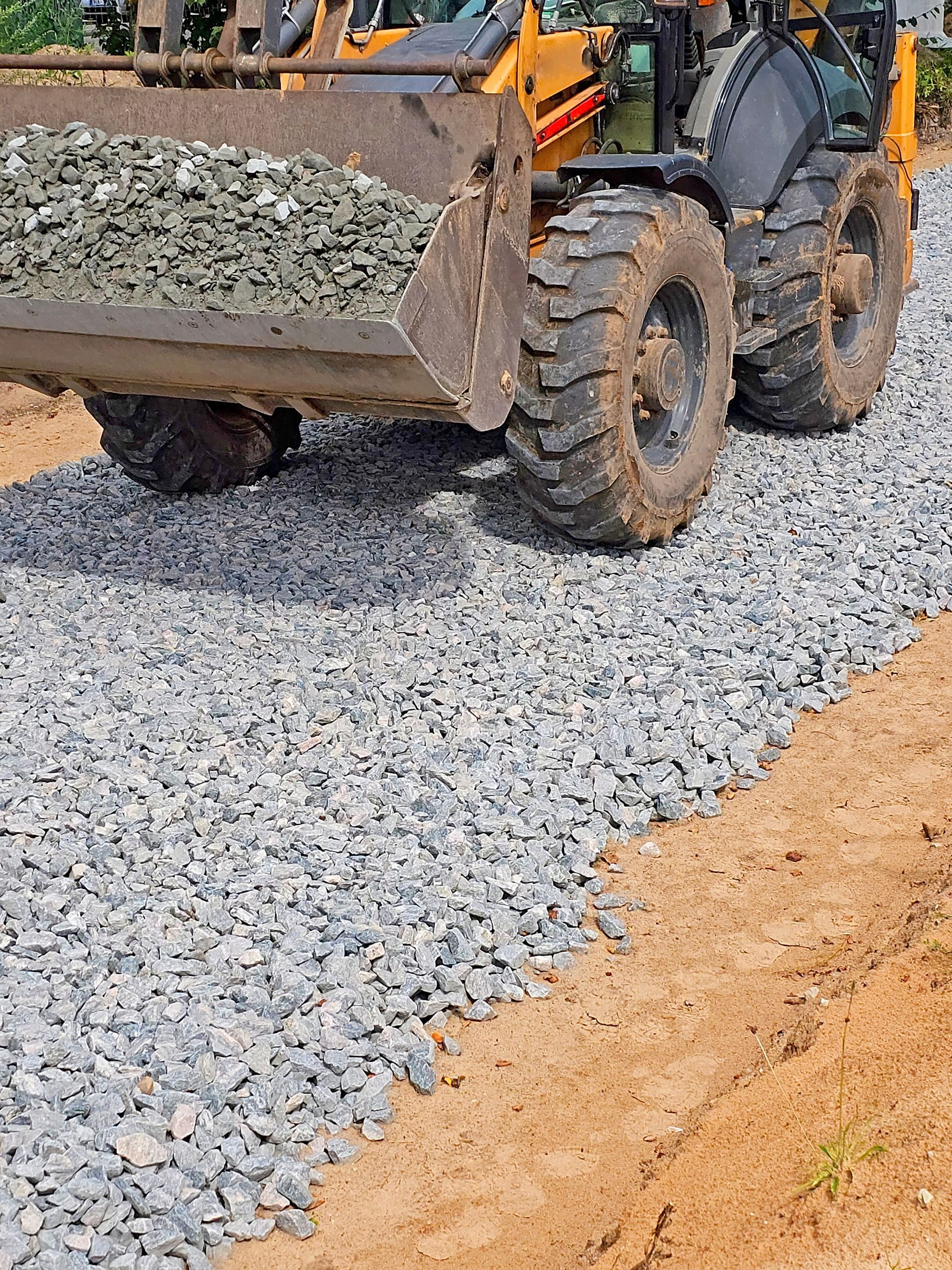 Loader dumping gravel onto a newly built roadbed.