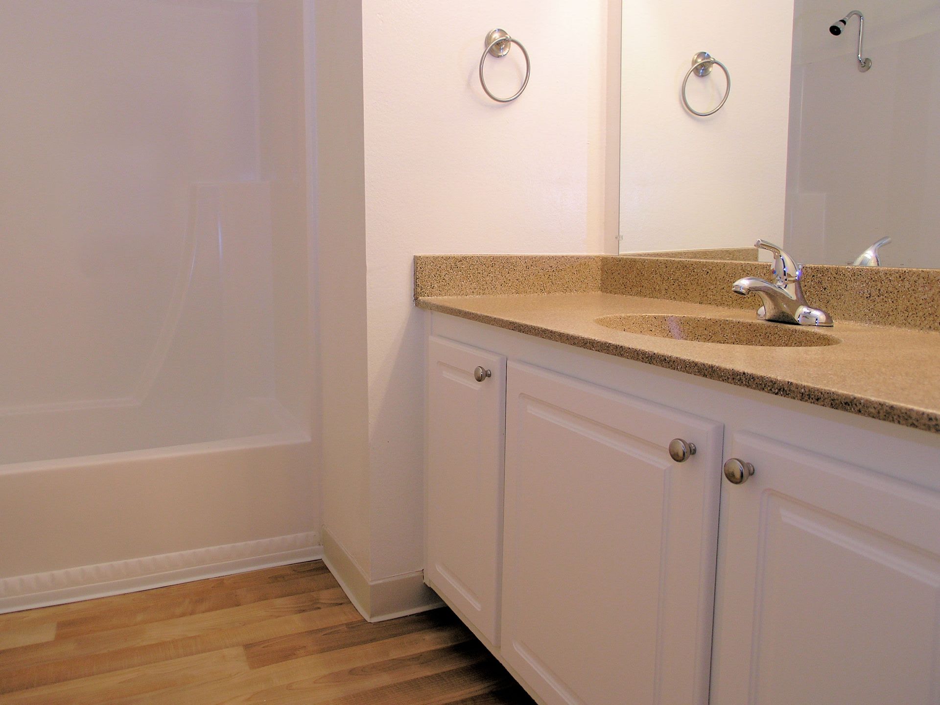 Bathroom vanity with beige countertop, white cabinets, and a mirror