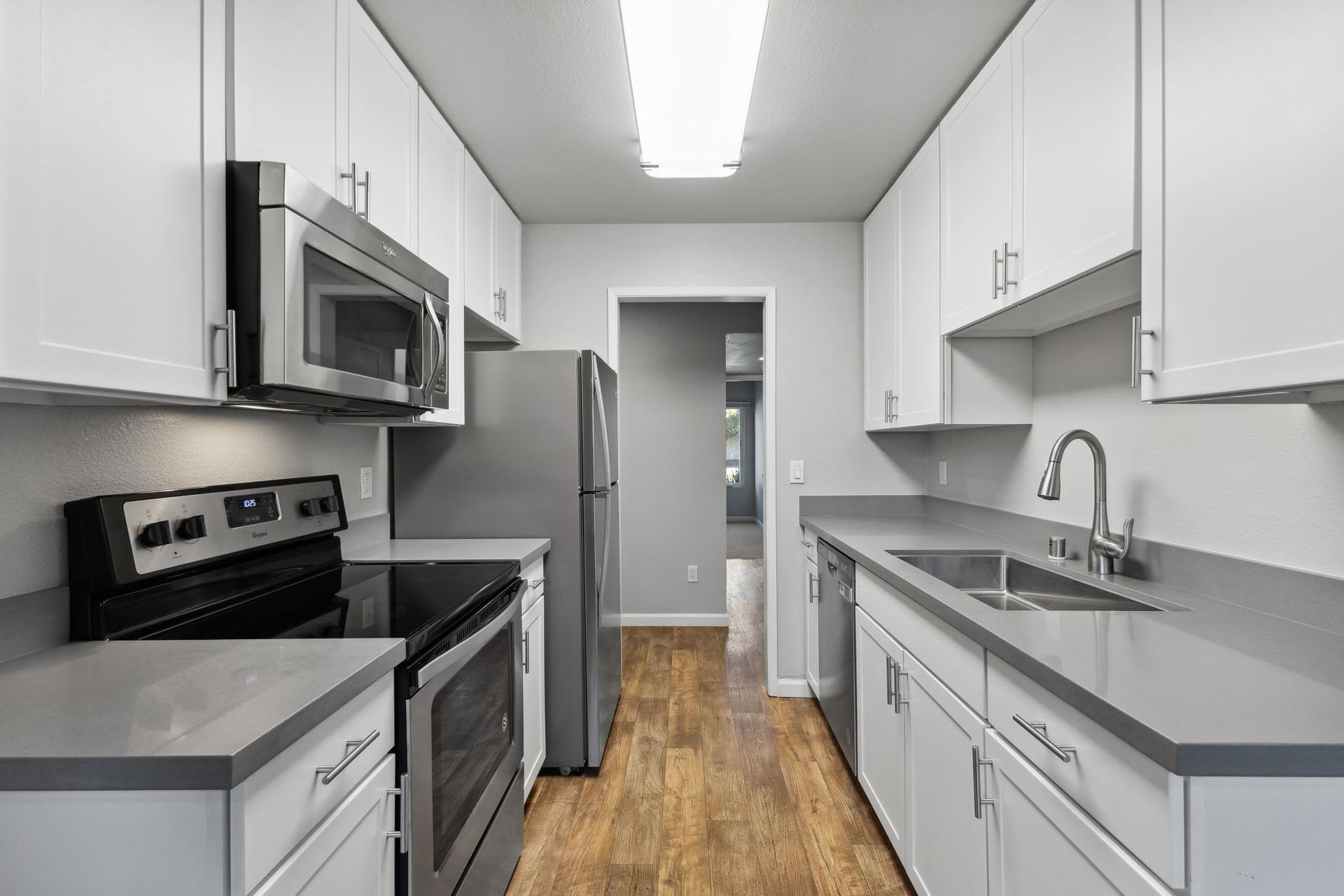 Galley kitchen with white cabinets, gray countertops, and stainless steel appliances.