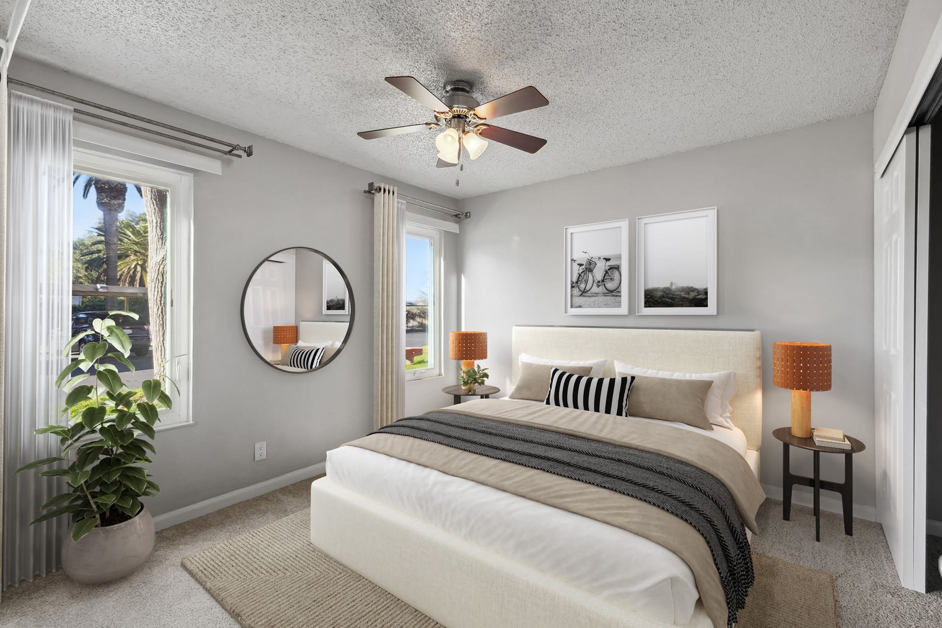 Bright bedroom with a queen bed, two bedside tables, ceiling fan, and large windows.