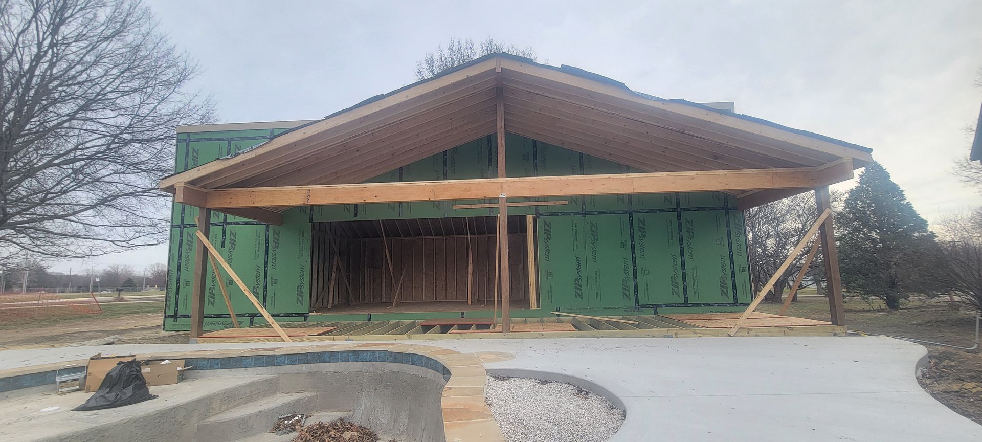 Construction of a building with a large wooden roof supported by beams and props. The exterior has green sheathing.