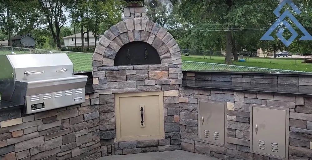 Outdoor Pizza Oven FAQ for KC Homeowners: Top 10 Questions Answered A pizza oven is built into a stone wall next to a grill.