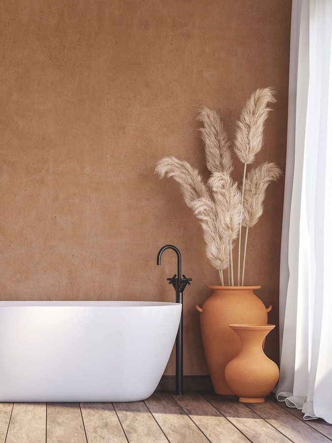 A bathroom with a bathtub , vases and pampas grass.