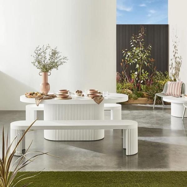 A white table with a vase of flowers on top of it.
