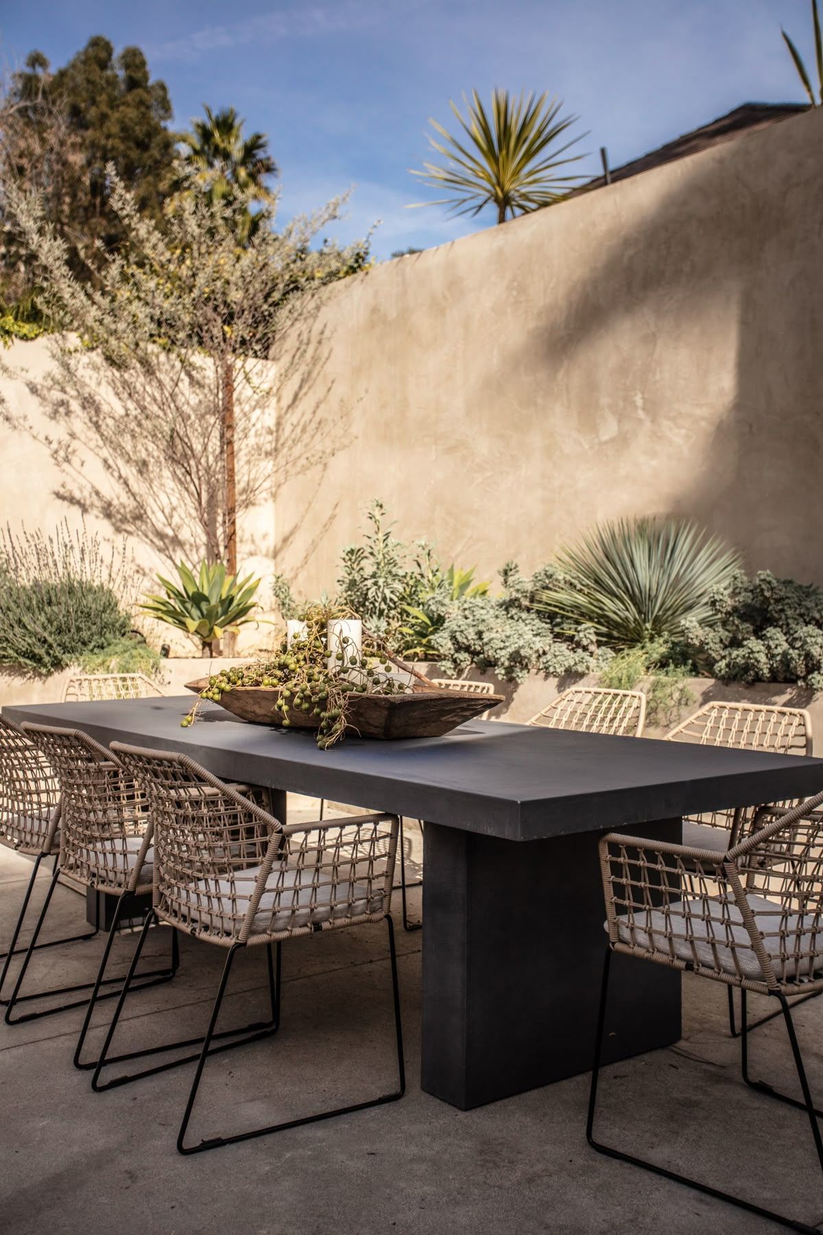 A patio with a table and chairs and a bowl of plants on it.