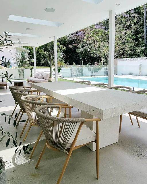 A table and chairs on a patio with a pool in the background
