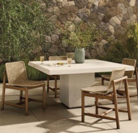 A table and chairs are sitting on a patio in front of a stone wall.