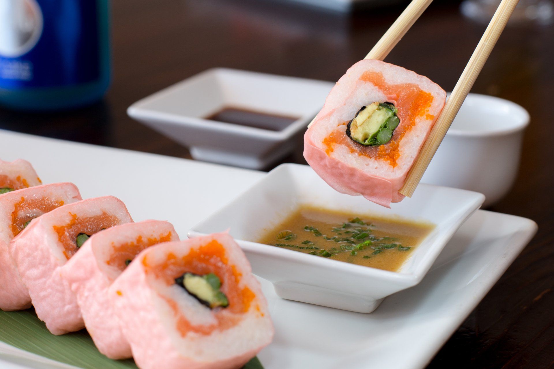 a person is taking a piece of sushi with chopsticks