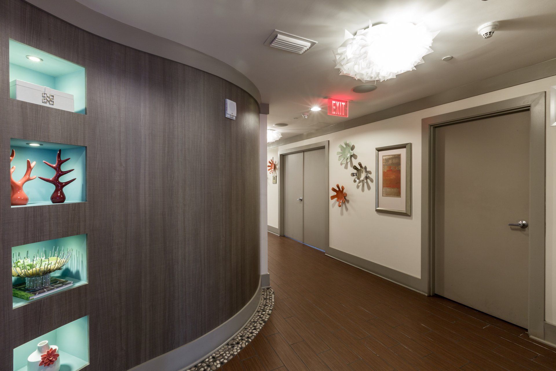 a long hallway with a red exit sign on the ceiling