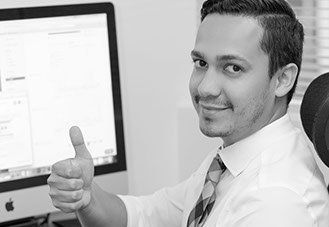 a man is sitting in front of a computer and giving a thumbs up .
