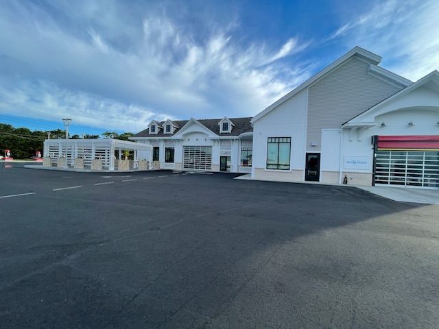Exterior of a white car wash with glass garage doors and a blue sky.