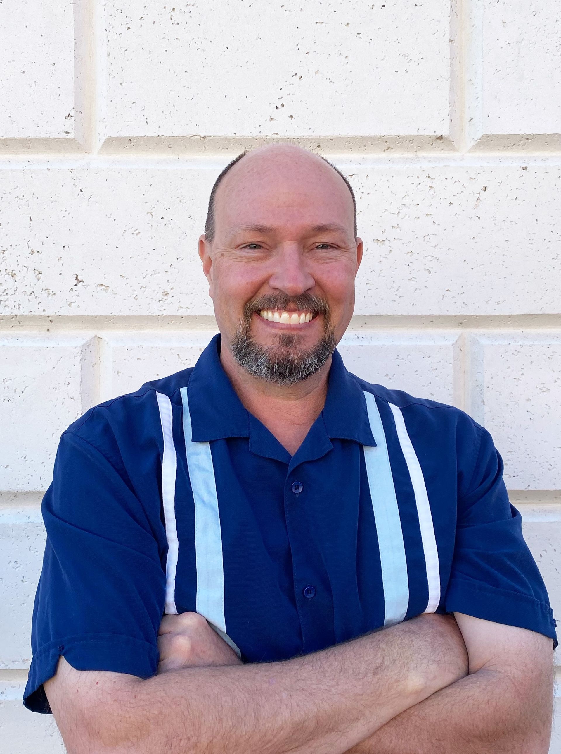 A woman is sitting at a desk with a laptop and a vase of flowers.