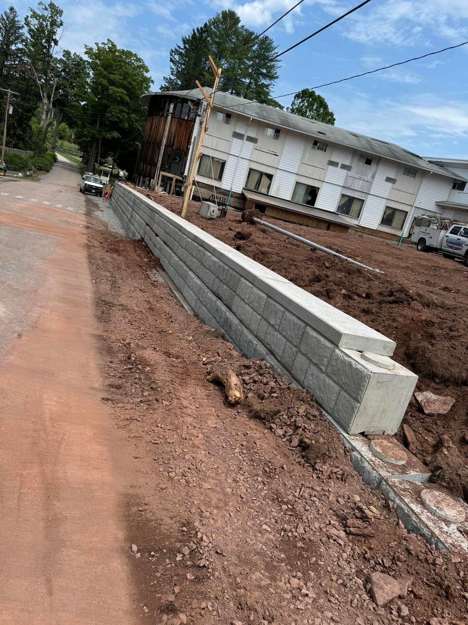 A newly constructed concrete block retaining wall beside a gravel path in front of a building under renovation.