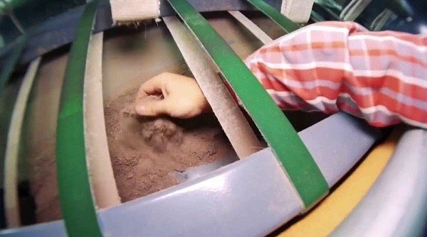 Person vacuuming a light-colored carpet with a handheld vacuum, leaving a clean path.