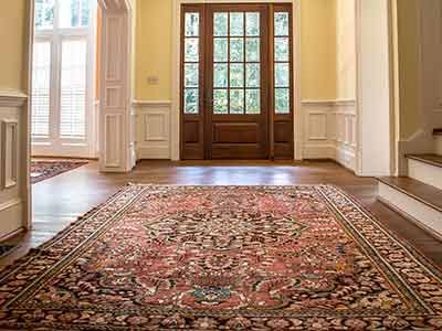 Oriental rug in a hallway with wooden door and large windows, wood floors, and yellow walls.
