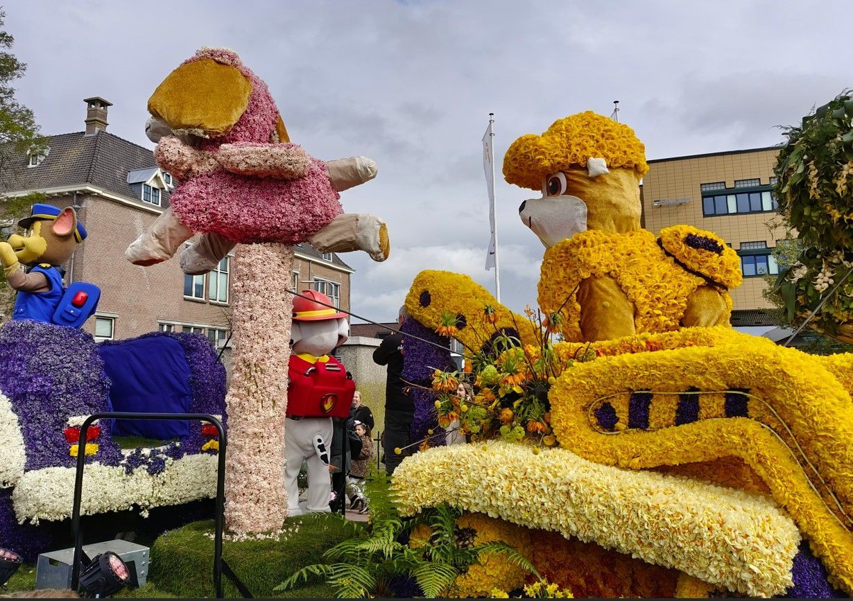 Kleurrijke, gigantische bloemensculpturen in een openluchtfestivaltentoonstelling onder een bewolkte hemel.