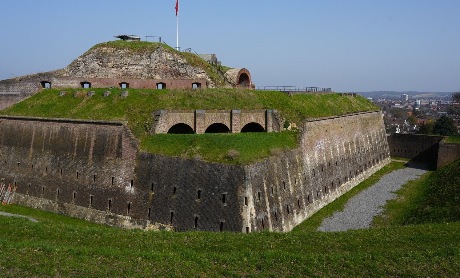De stenen vesting heeft met gras begroeide wallen en een trapsgewijs opgebouwd bakstenen bastion.