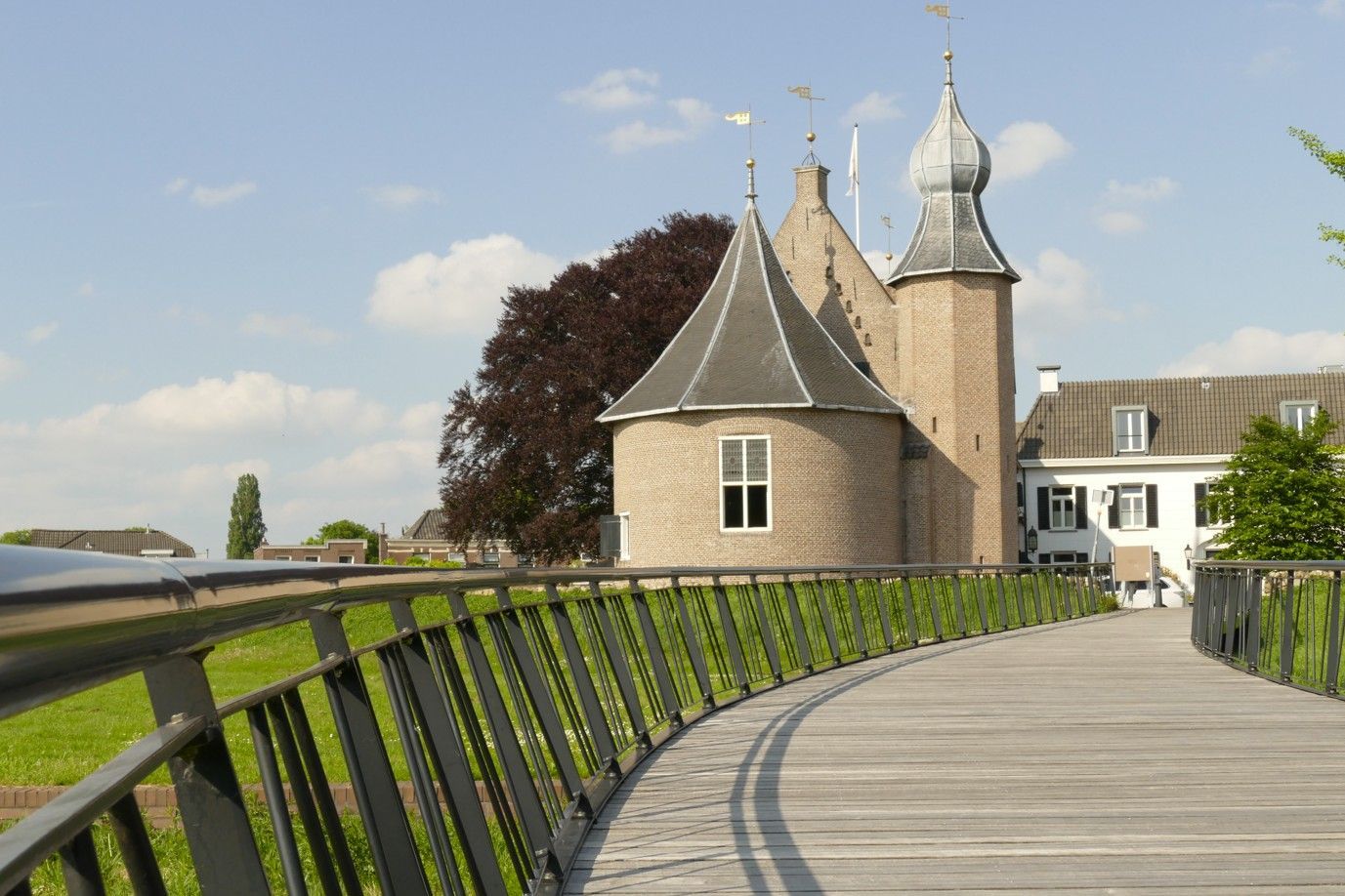 Stenen kasteel met een wandelpad op de voorgrond, tegen een blauwe hemel met enkele wolken.