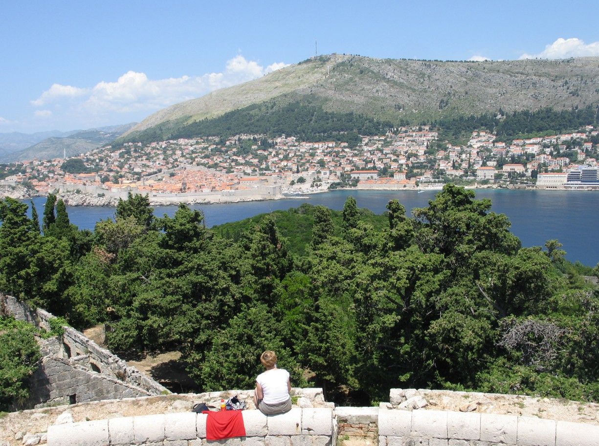 Een persoon zit en kijkt uit over de stad Dubrovnik in Kroatië en de Adriatische Zee.