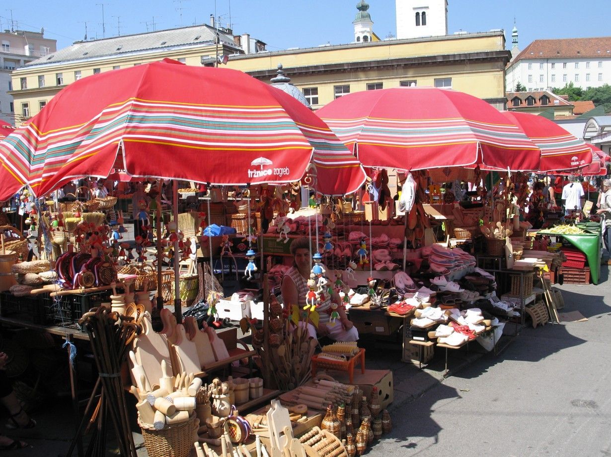 Marktstalletjes met rode parasols, waar handwerk en souvenirs worden verkocht op een stadsplein.