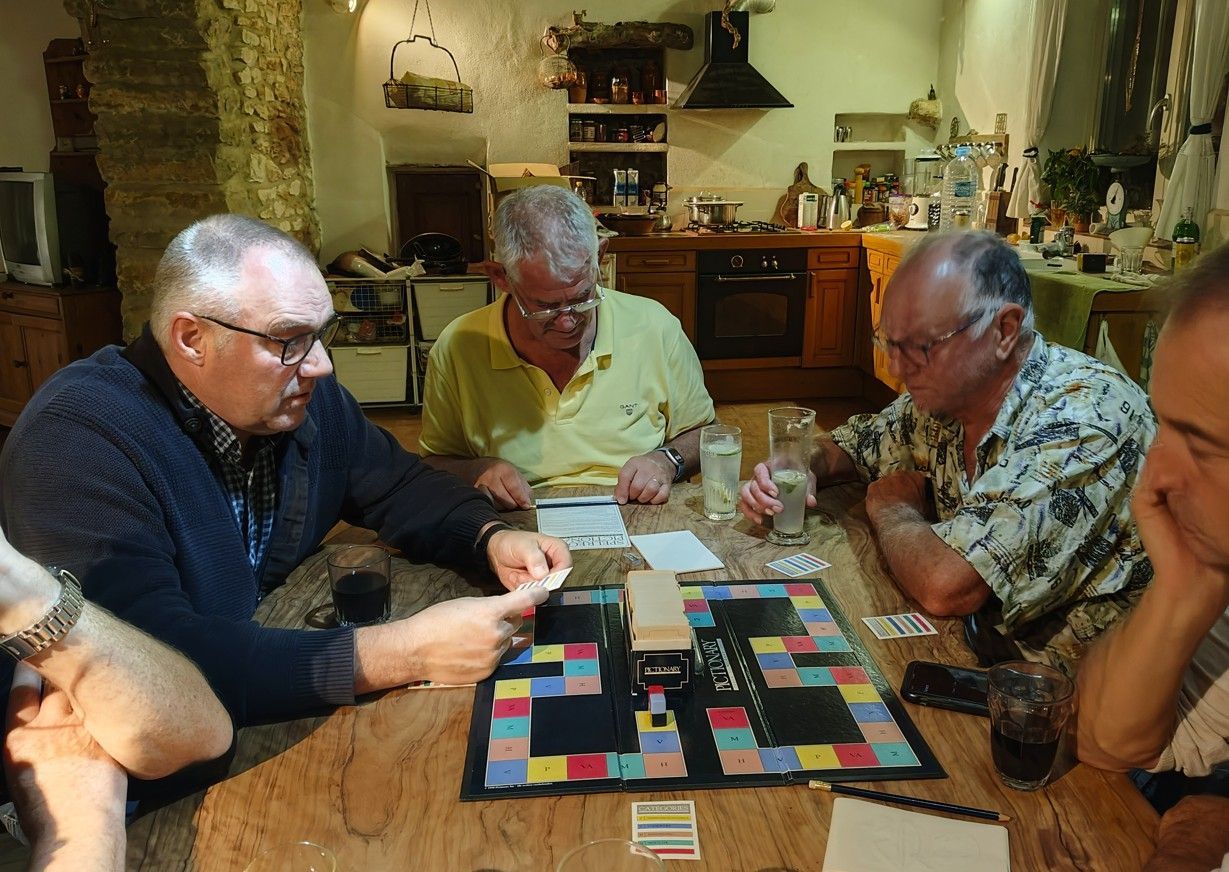 Mannen spelen een bordspel aan een houten tafel in een keuken.