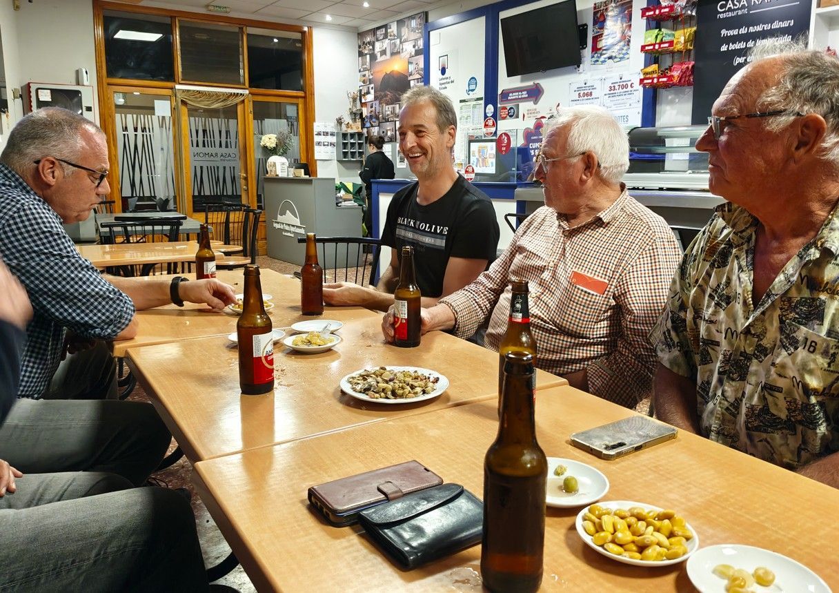 Vier mannen zitten aan een tafel in een bar, bier te drinken en snacks te eten.