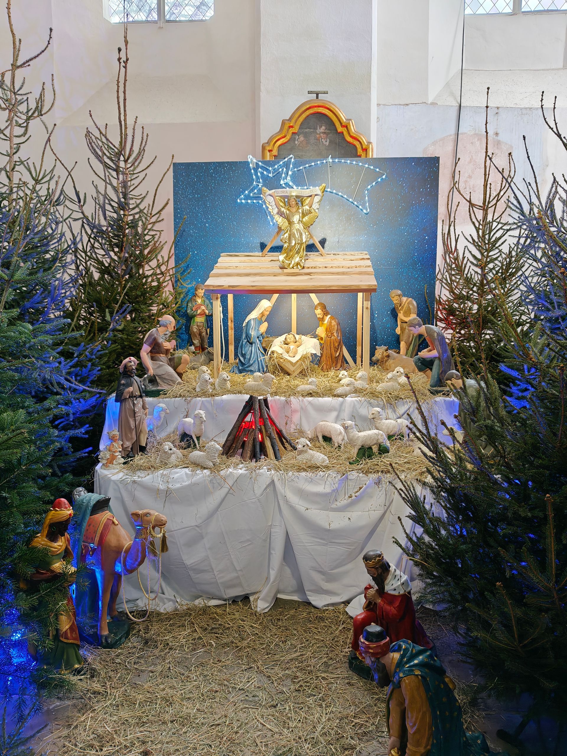 Kerststal in een kerk met de figuren van Maria, Jozef, het kindje Jezus en de drie wijzen.
