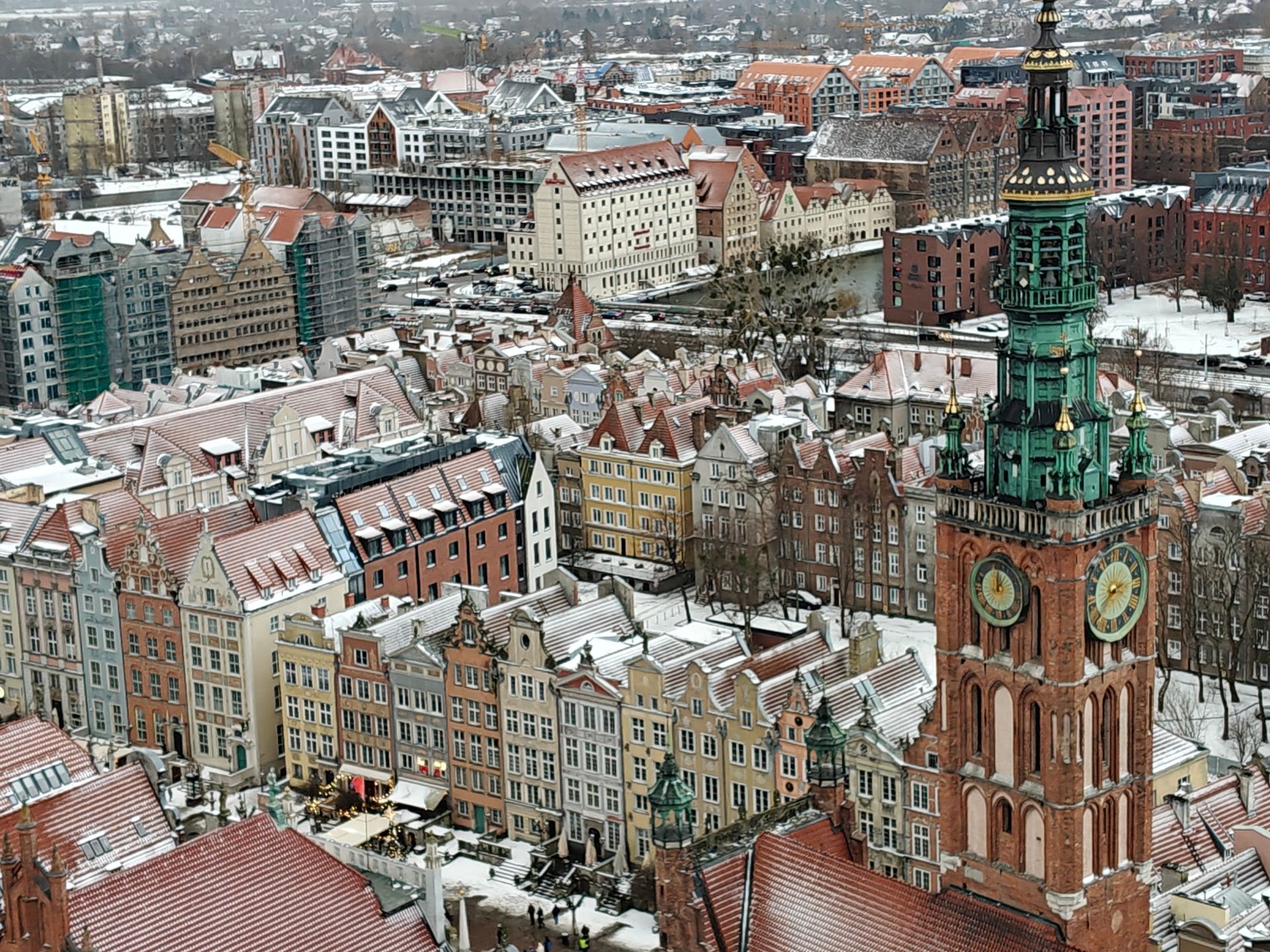 Luchtfoto van het besneeuwde Gdansk, Polen, met kleurrijke gebouwen en een opvallende klokkentoren.