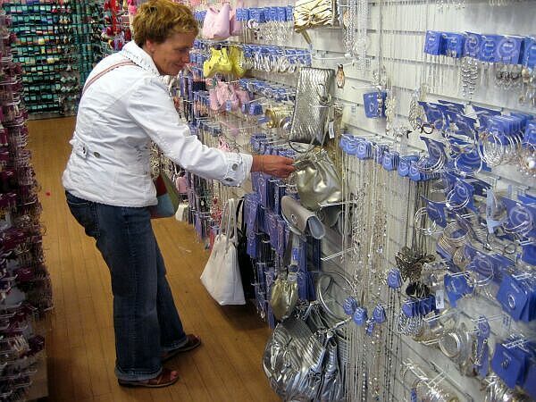 Een persoon bekijkt ophangaccessoires in een winkelgang met rijen verpakte artikelen en blauwe haken.