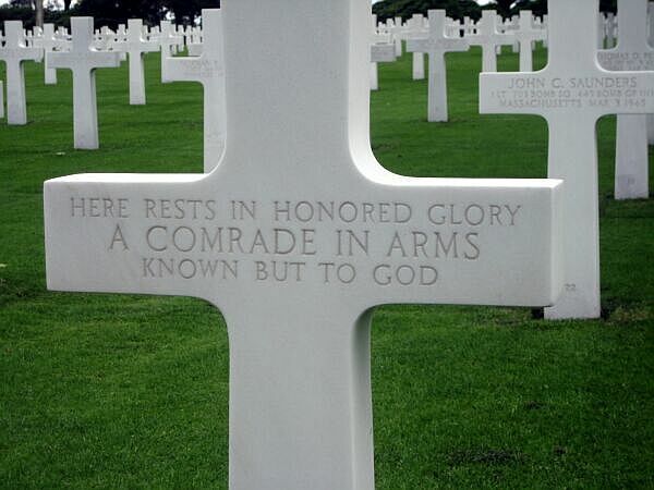 Witte militaire grafsteen op een begraafplaats met gegraveerde tekst.