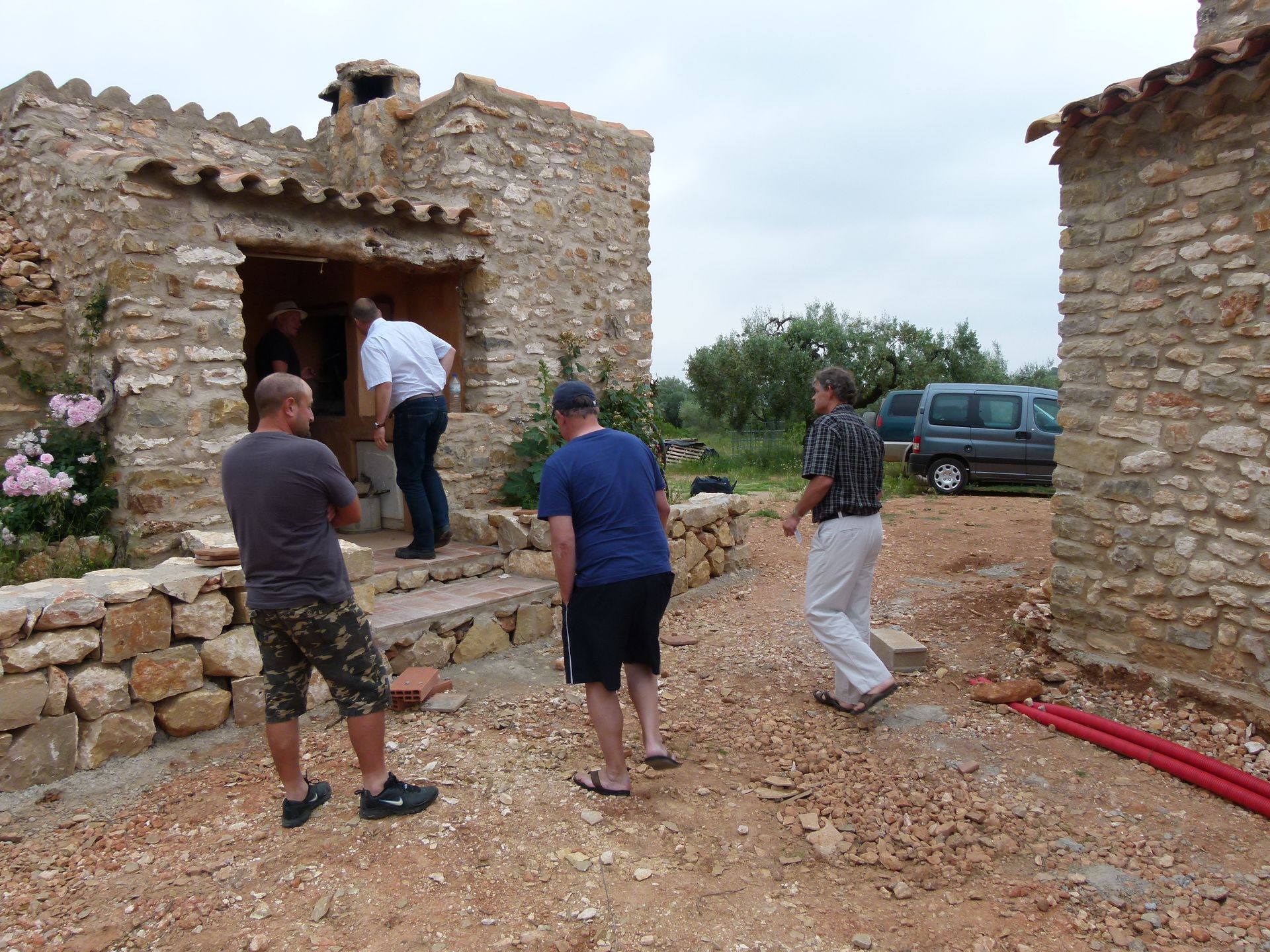 Mensen in de buurt van stenen gebouwen in aanbouw; grindterrein.