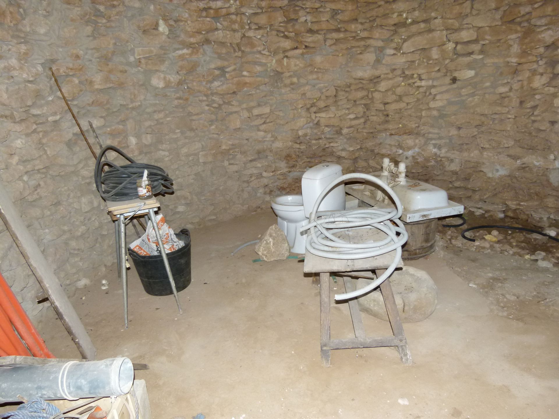 Grotinterieur met diverse bouwgereedschappen en -materialen, waaronder een toilet en een wastafel.