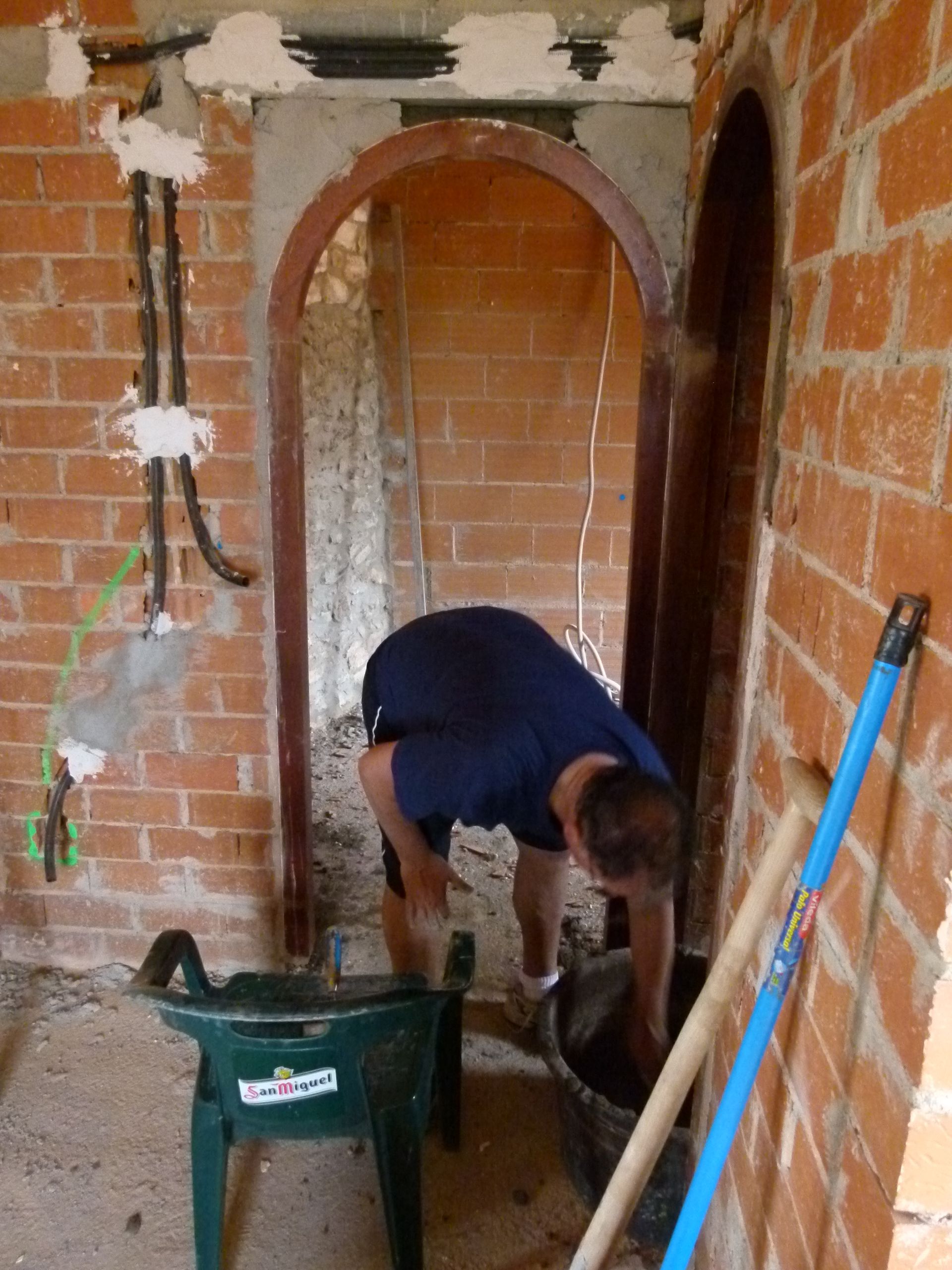 Man werkt aan een bakstenen deuropening, mengt materiaal in een kuip, op een bouwplaats voor interieurwerkzaamheden.