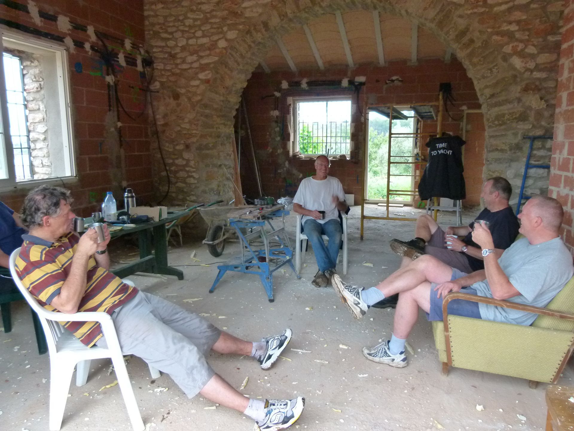 Mensen ontspannen zich in een gebouw van baksteen en natuursteen, genieten van een drankje en voeren een goed gesprek.