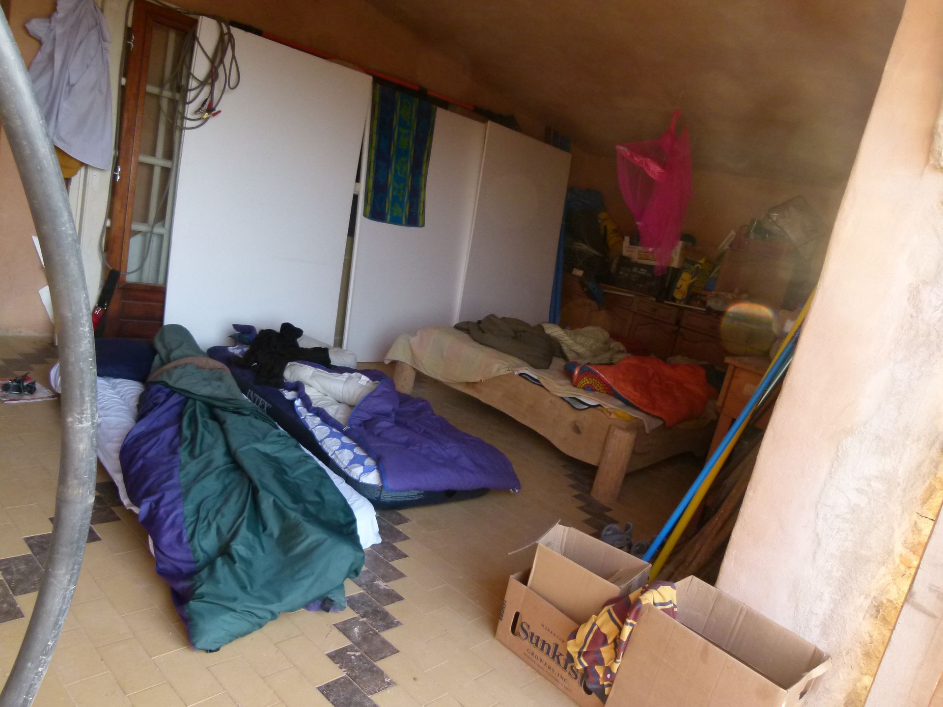 Kamer met slaapzakken, bed en kartonnen dozen.