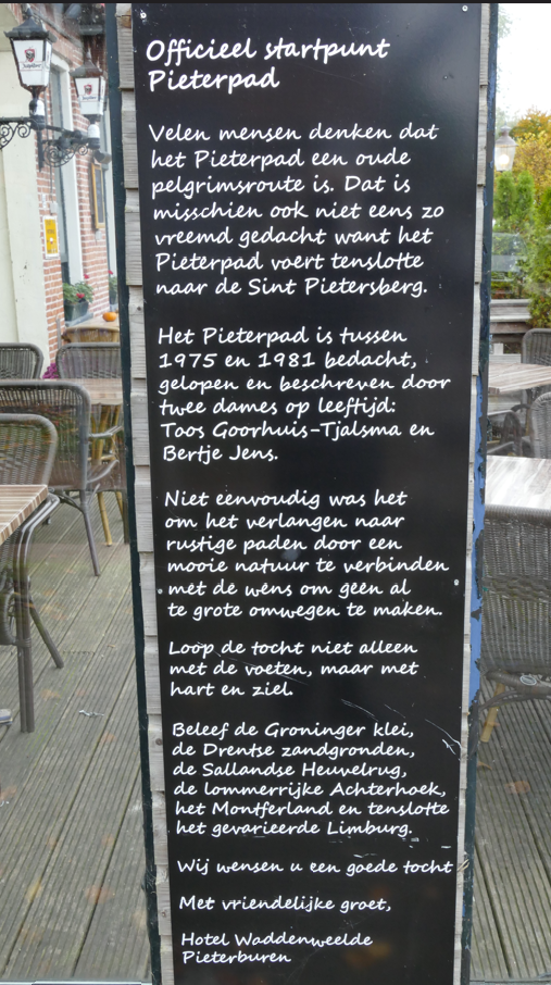 Zwart bord met witte tekst, dat het officiële startpunt van de Pieterpad-wandelroute markeert.
