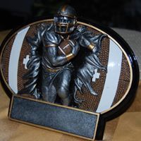 A statue of a football player holding a football is sitting on a wooden table.