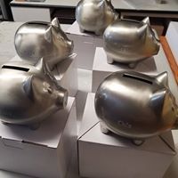 A group of silver piggy banks sitting on top of white boxes.