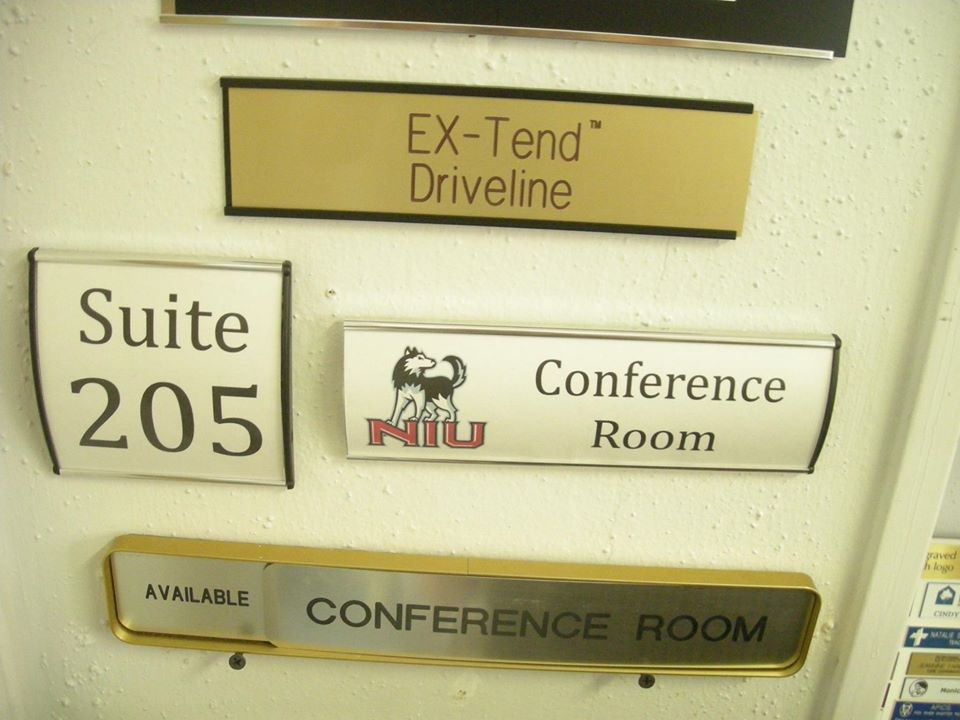 Several signs on a wall including one for the conference room