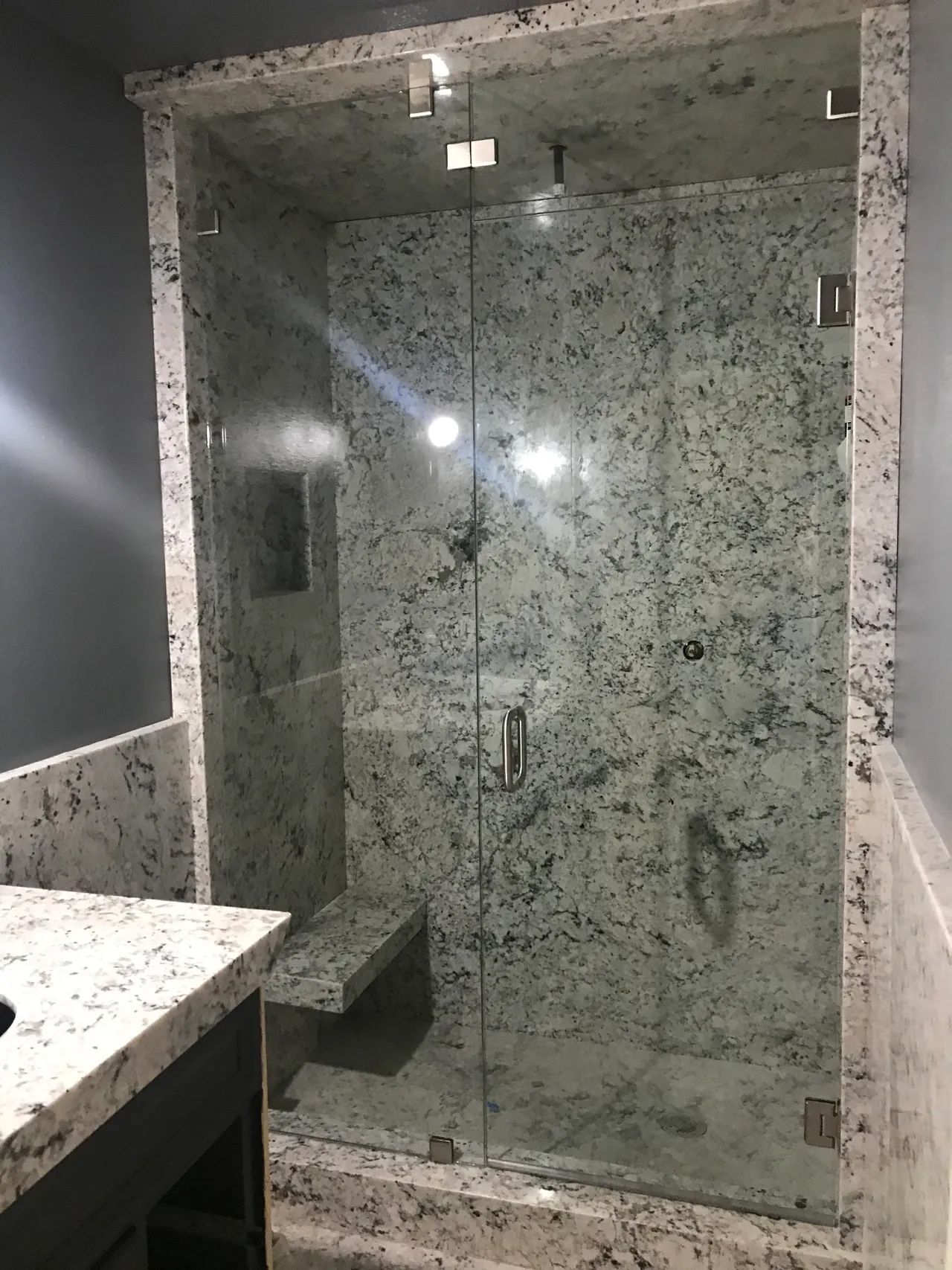 A bathroom with a walk in shower and a sink