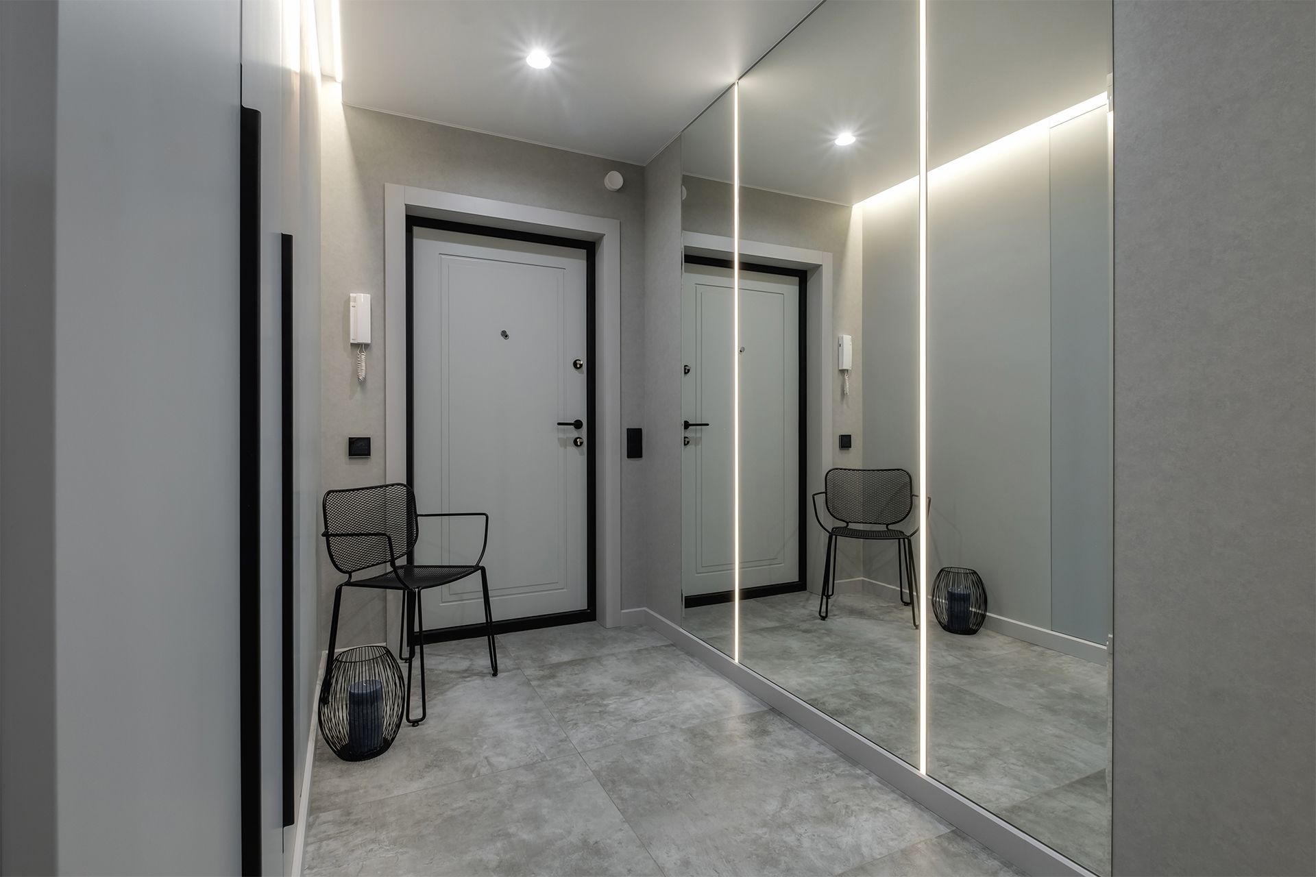A hallway with a large mirror on the wall and a chair