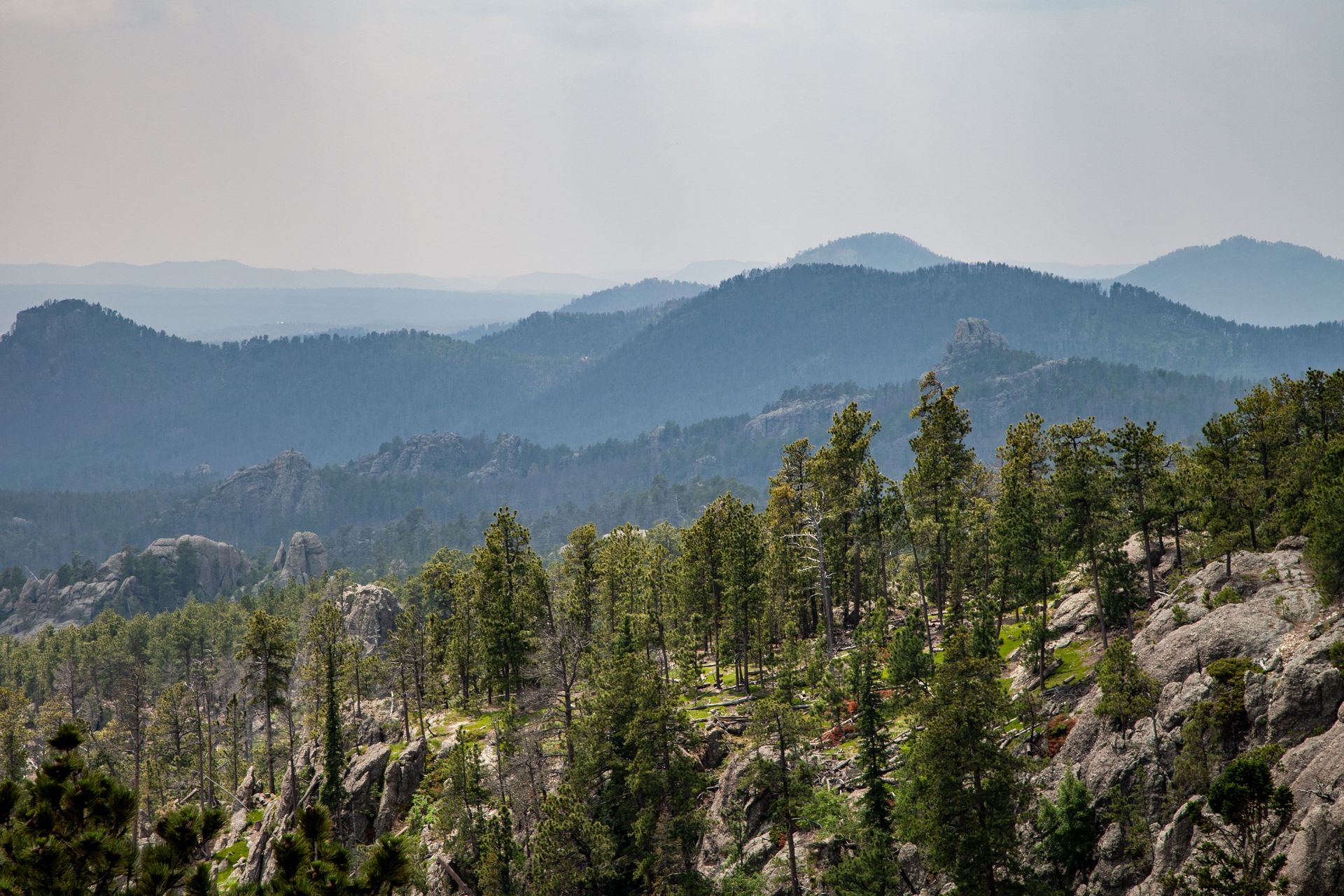 Mountain range with layers of forested hills under a hazy sky.