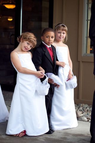 Two flower girls and a ring bearer are posing for a picture